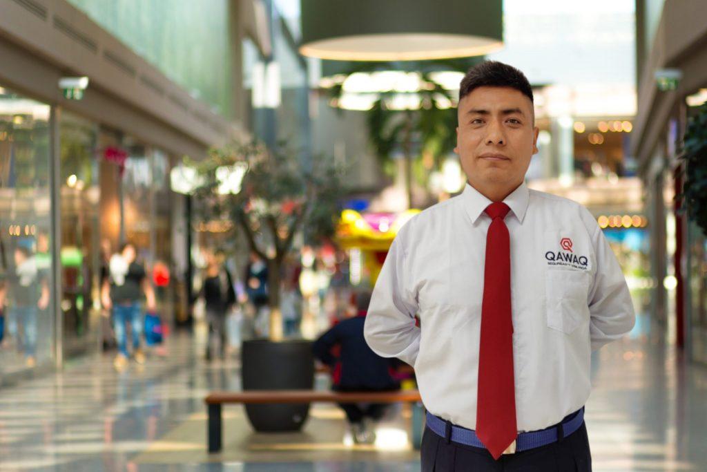 Persona evacuando de manera segura durante un sismo en un centro comercial, siguiendo las indicaciones de un vigilante de seguridad.